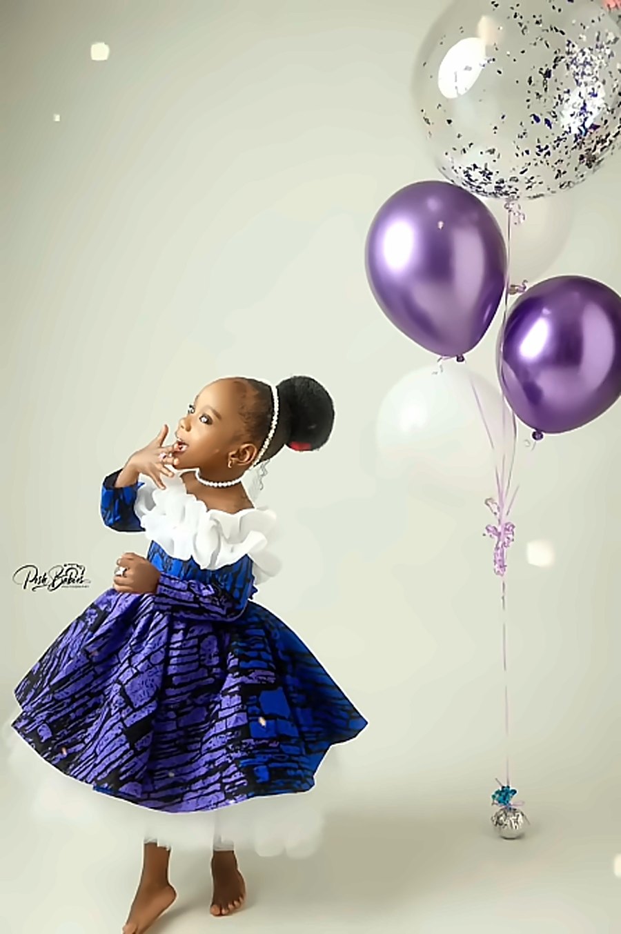 A girl in a purple ankara dress with balloons